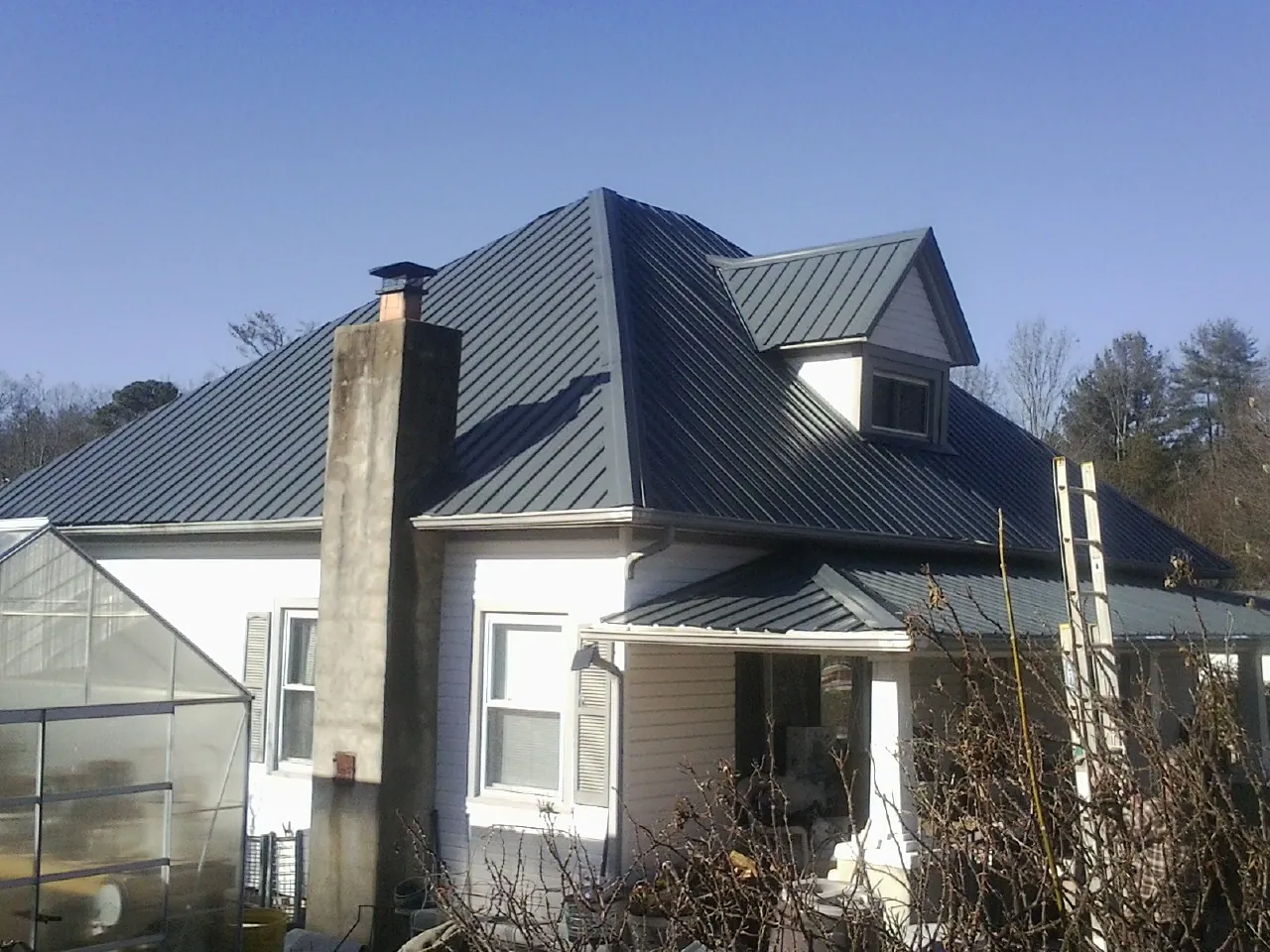 Dark blue standing seam metal roof on a white farmhouse with dormer — Slate & Tile Roof Repair by Roofing Brothers in Hiawassee