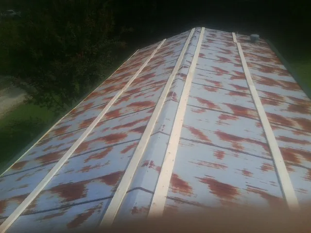 Rusted metal roof panels with new wood purlins before replacement — Storm Damage Roof Repair in Hiawassee by Roofing Brothers