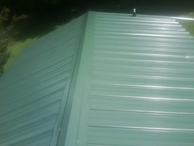 New green metal panels meeting at the ridge of a roof — Flat Roof Repair work by our crew in Hiawassee
