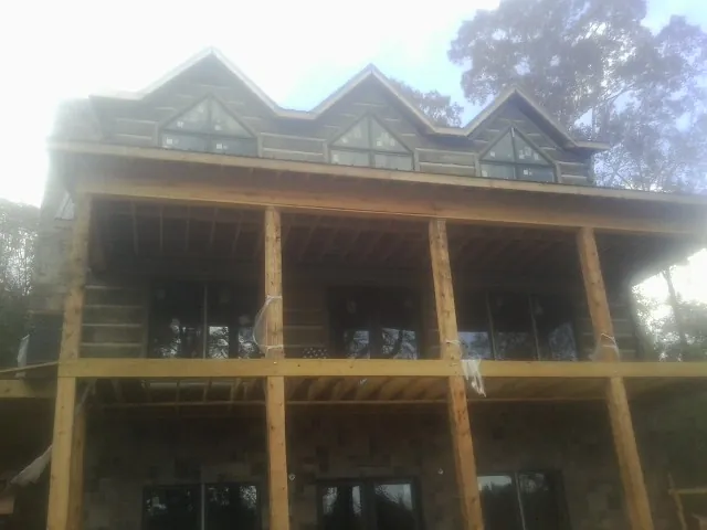 Dormers and porch framing on a large log home under construction — Roof Coating work by our crew in Hiawassee