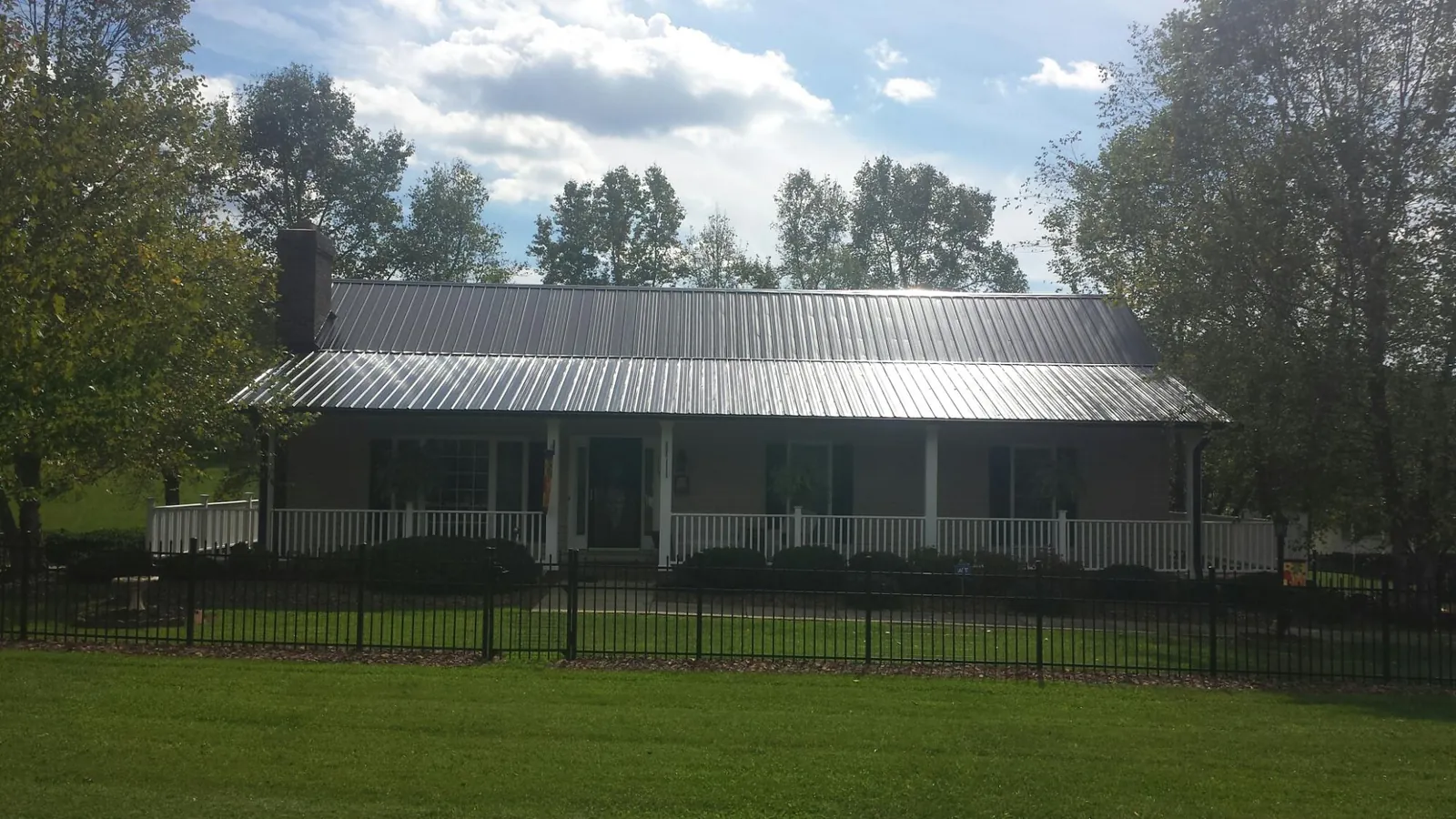 Gray metal roof on a brick ranch with a full width front porch — Gutter Guard Installation work by our crew in Hiawassee