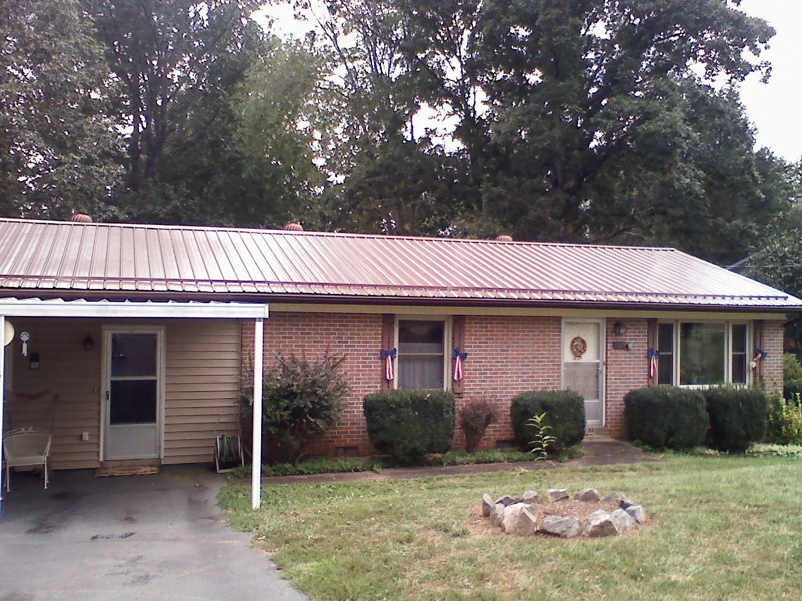 Bronze metal roof and carport on a brick ranch home — Roof Repair work by our crew in Hiawassee