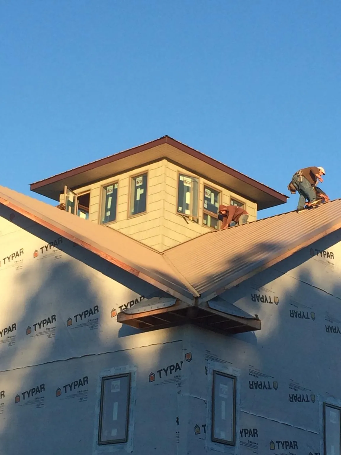 Roofers working around a rooftop cupola on a new metal roof at sunset — Roof Waterproofing in Hiawassee by Roofing Brothers
